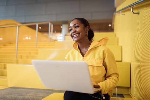 mujer joven sentada en pasos usando laptop y sonriendo