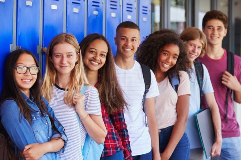 grupo de estudiantes de primer año de secundaria apoyados en casilleros