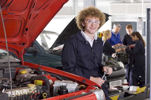 student in auto shop next to vehicle with hood raised