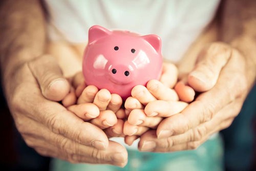 piggy bank being held by 3 different sized sets of hands