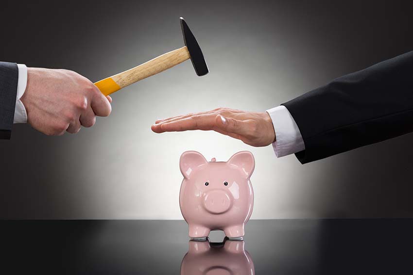 Person stopping someone from breaking piggy bank with hammer