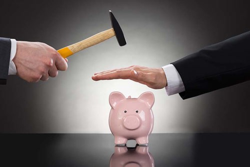 Person stopping someone from breaking piggy bank with hammer
