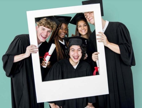 grupo de estudiantes de último año de secundaria en sus gorras y vestidos sosteniendo un accesorio de marco de fotos