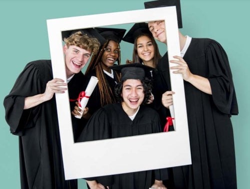 grupo de estudiantes de último año de secundaria en sus gorras y vestidos sosteniendo un accesorio de marco de fotos